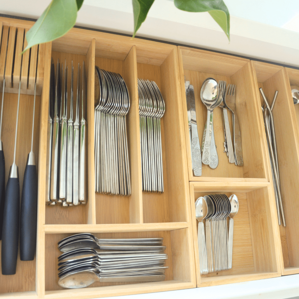 organisering i skuffen i med skuffekasser | Wooden cutlery drawer with multiple compartments, neatly organized with forks, knives, and spoons in each slot. Aflang skuffeindsats i bambus med bestik organiseret i en køkkenskuffe.