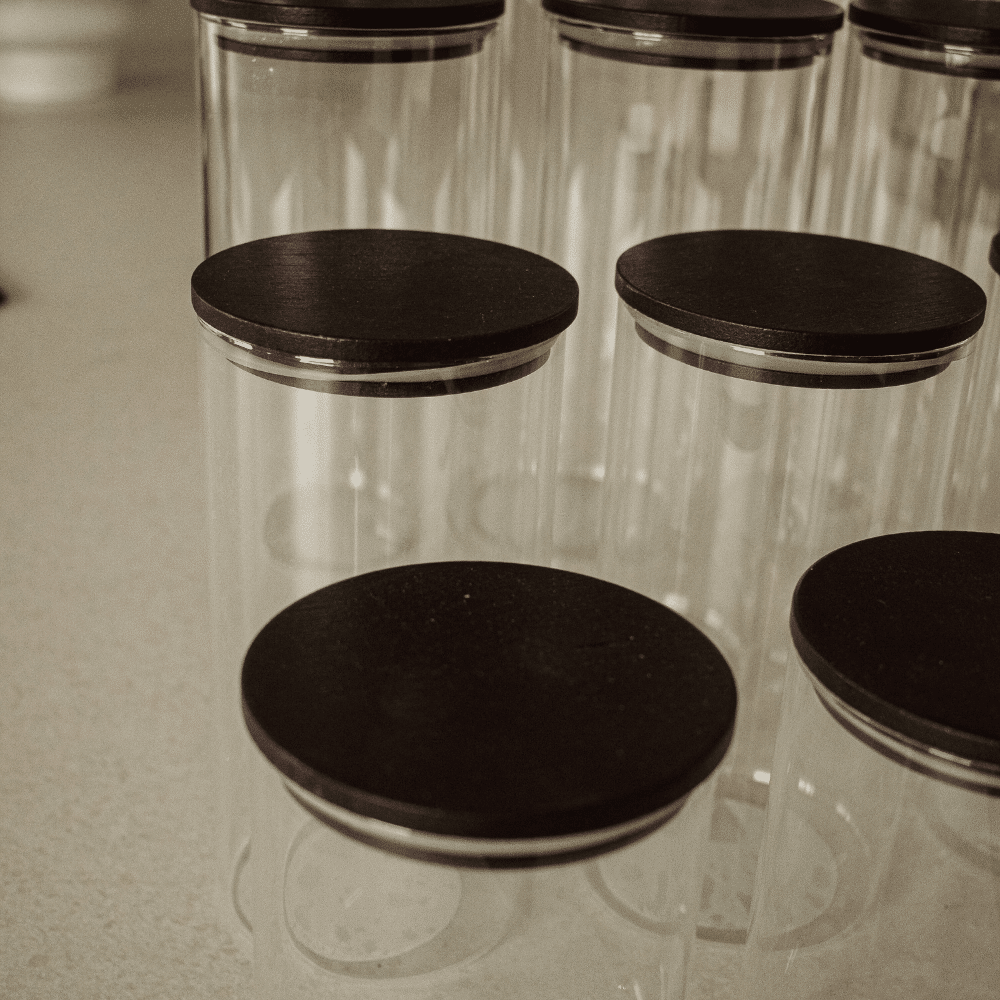 låg med silikone pakning for undgå skadedyr | Detaljebillede af sort bambuslåg med silikonepakning på rundt opbevaringsglas i borosilikatglas.