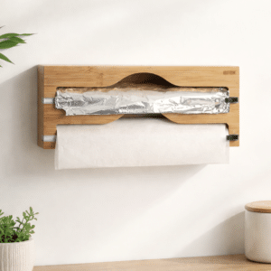 Foliedispenser i bambus med to skær hængende på køkkenvæg med aluminiumfolie og husholdningsfilm
